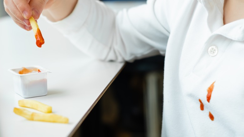 child eating French fries with ketchup and stain on clothes