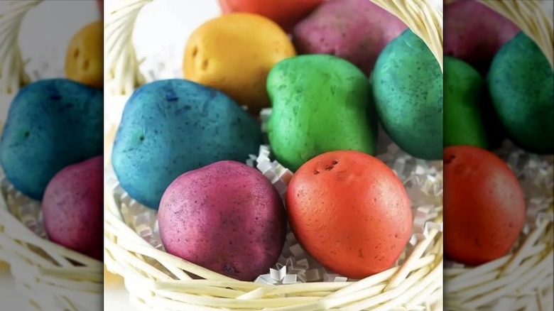 Colorfully dyed whole potatoes in a wicker basket.