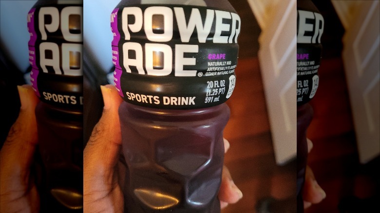 Someone holding Powerade Grape bottle