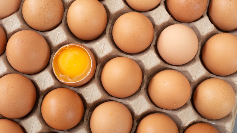 Extra large carton of eggs with one cracked open egg