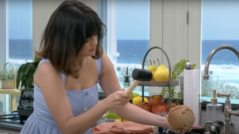 Selena Gomez hitting a coconut with a hammer