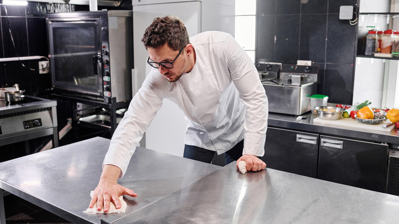 chef in a restaurant kitchen cleaning the counter