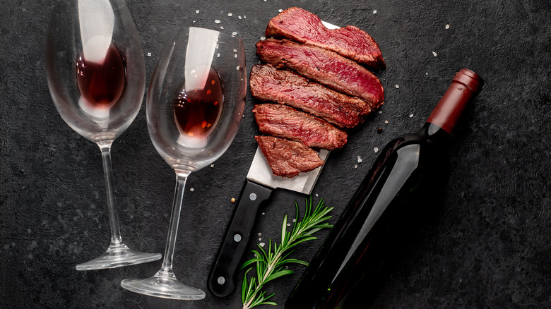 Cut, rare steak with red wine in glasses