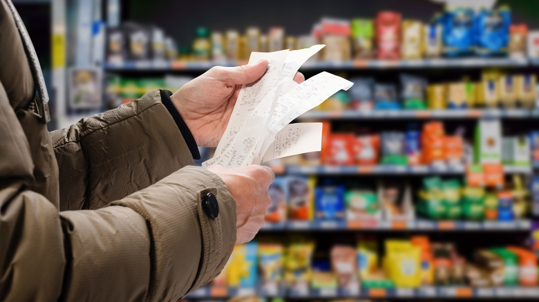 Hands holding receipts in a grocery store