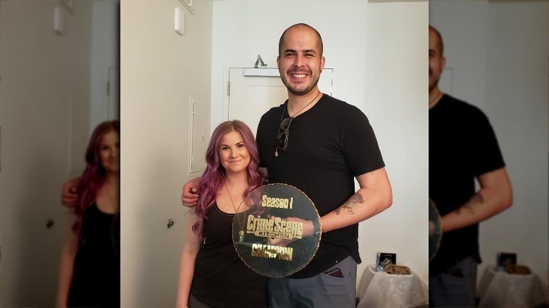 Natalie and Luis holding the winner's cake stand