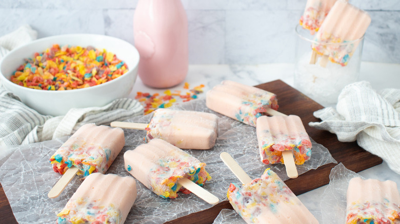 pink popsicles with Fruity Pebbles on a wooden board