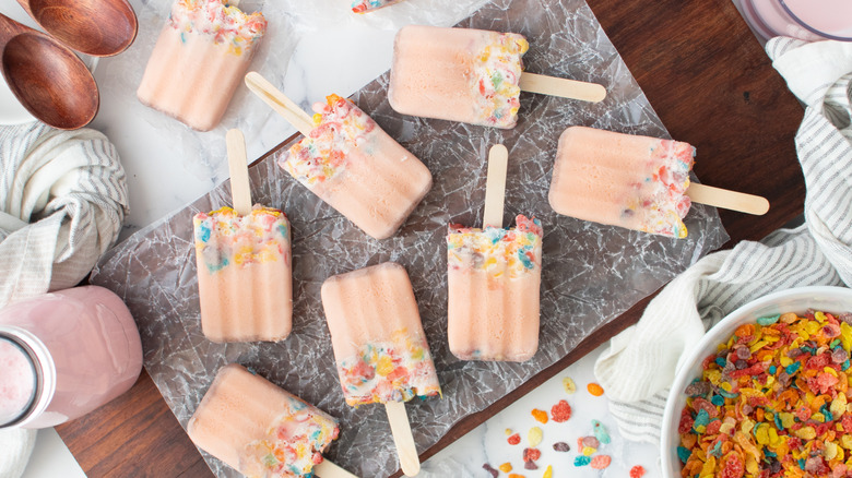 pink popsicles with Fruity Pebbles on wooden board