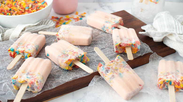 pink popsicles with Fruity Pebbles on a wooden board