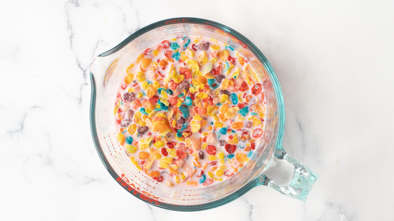 Fruity Pebbles cereal in cup of milk