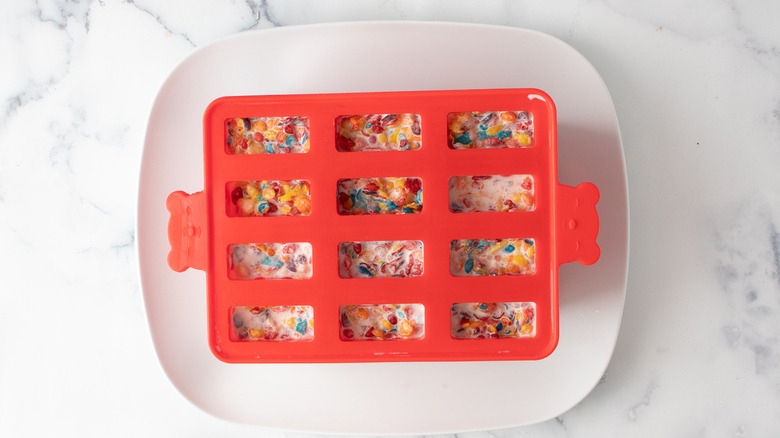 red plastic popsicle molds with popsicle mixture