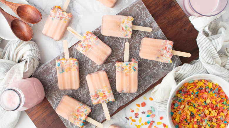 pink popsicles with Fruity Pebbles on a wooden board