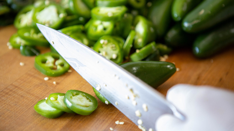 knife slicing jalapeno peppers