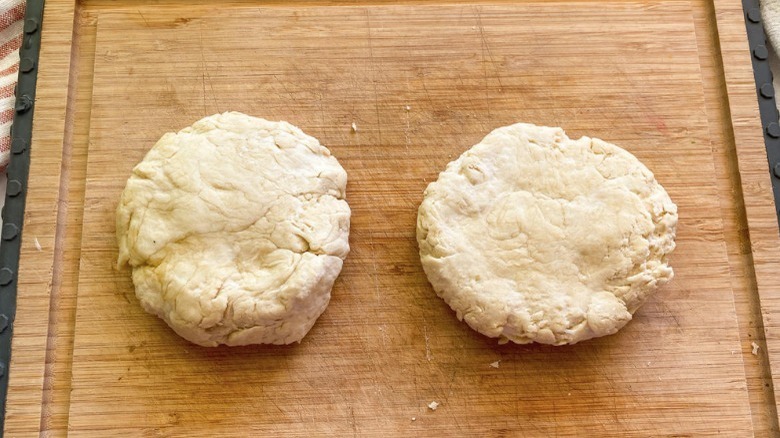 pizza dough halves on cutting board