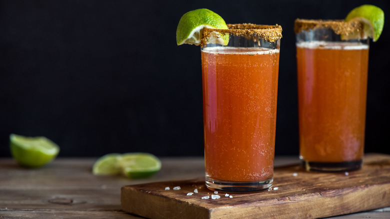 Michelada cocktail on board with limes