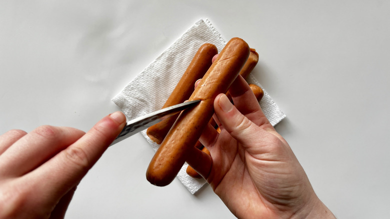 hand cutting hot dog