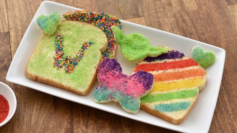 Pieces of fairy bread on a plate, white bread covered with butter and sprinkles