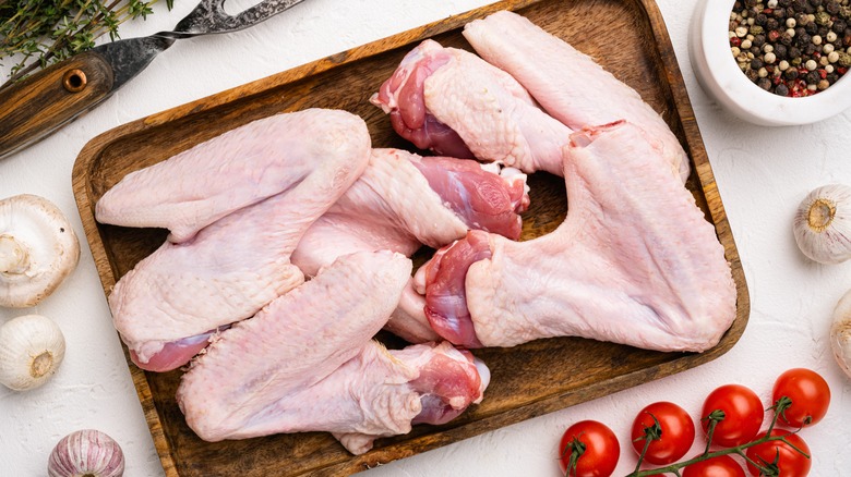 Raw duck wings on wooden plate