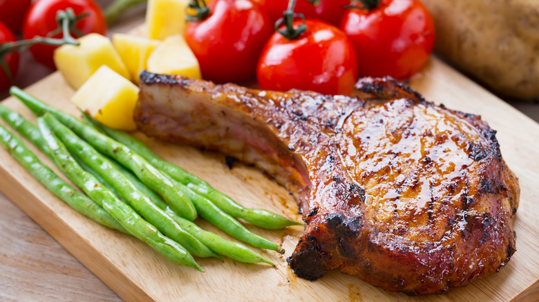 Smoked pork chop on cutting board with vegetables