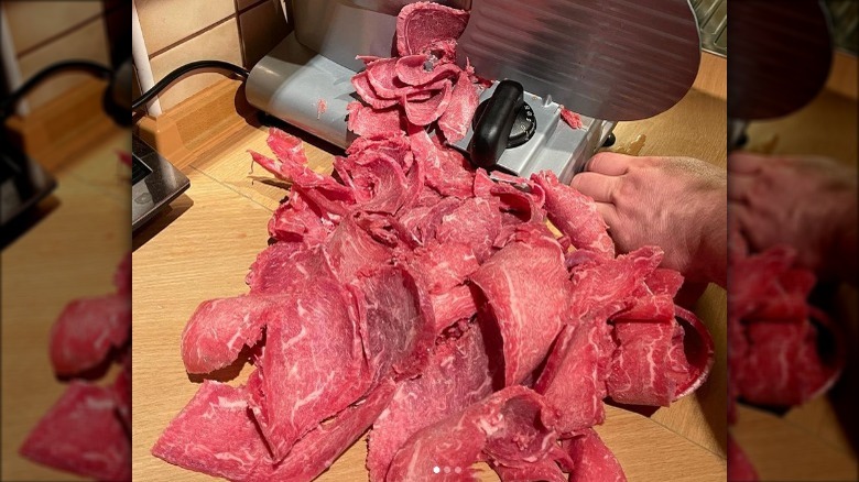 Meat slicer slicing beef flank steaks