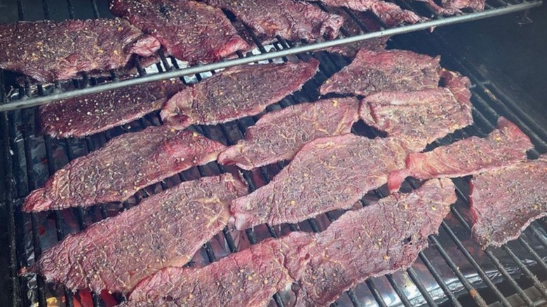 Slices of top round for beef jerky on a grill