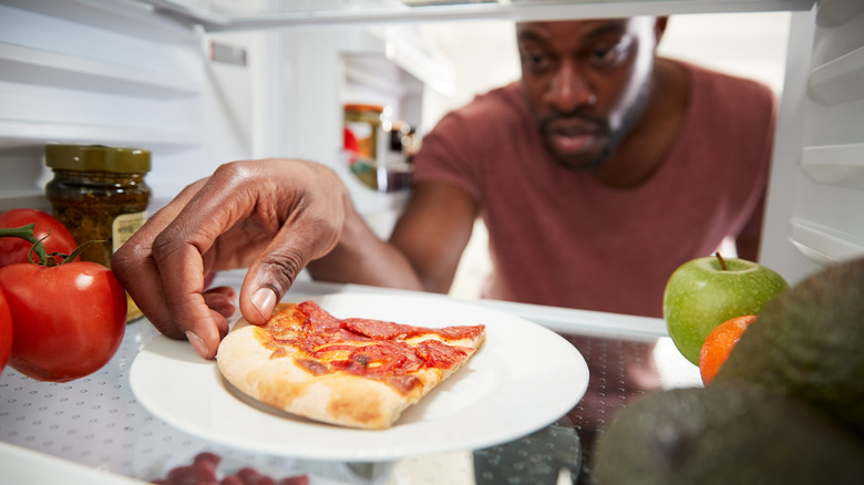 Man taking pizza from refrigerator 