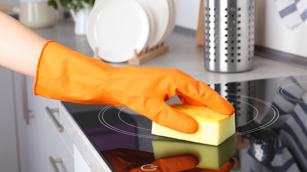 Gloved hand cleaning stovetop