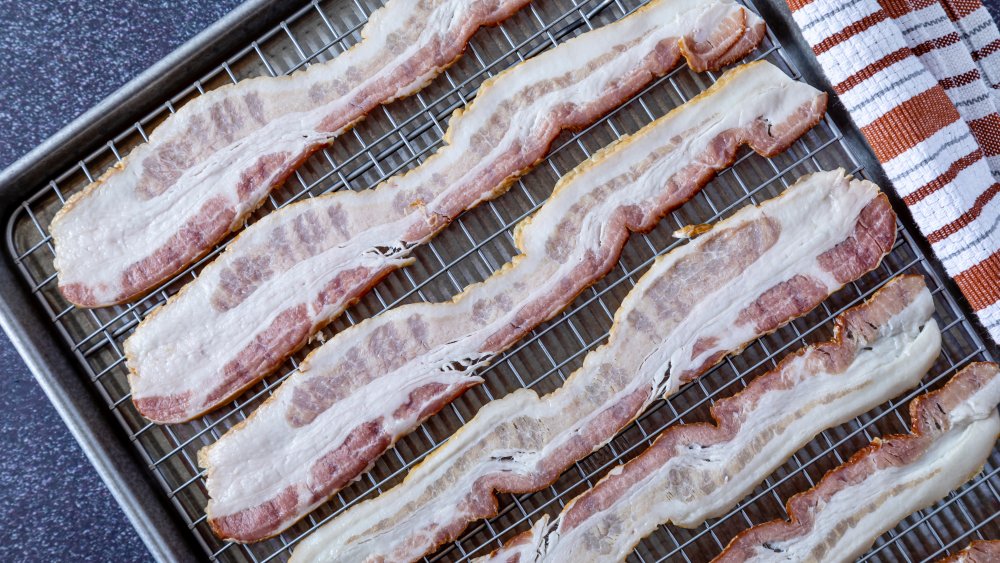  Raw slices of bacon on a wire rack set in a rimmed baking sheet.