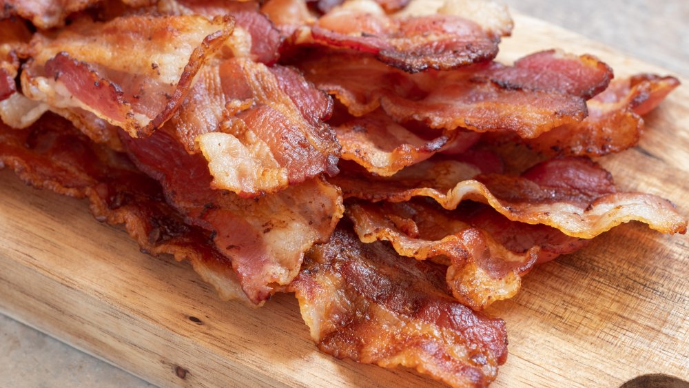 Close up of cooked bacon slices on a cutting board.