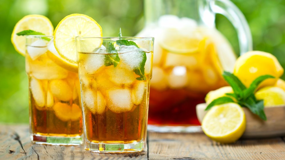 Glasses of iced tea with lemon and mint, pitcher in back