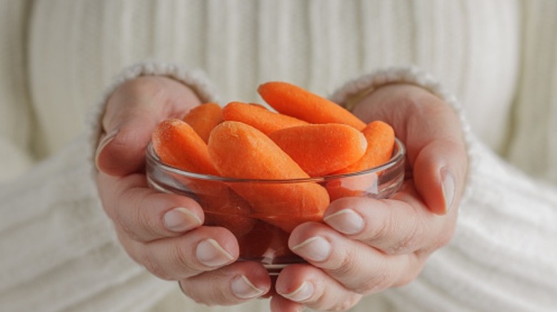 woman holding bowl of baby carrots