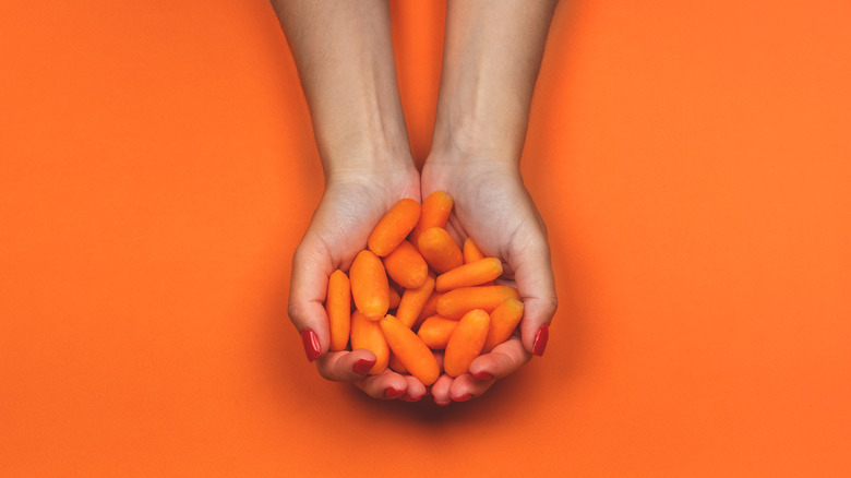 person holding baby carrots