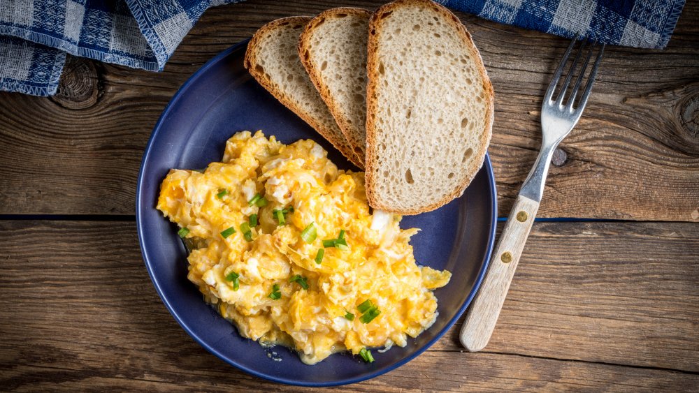 A plate of scrambled eggs with toast 