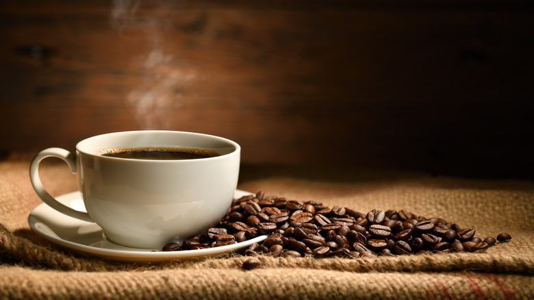 Mug of black coffee with coffee beans