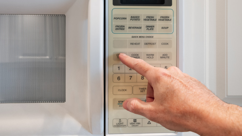 Hand pushing button on microwave