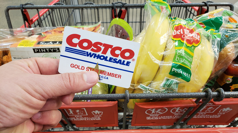 Hand holding Costco card and shopping cart