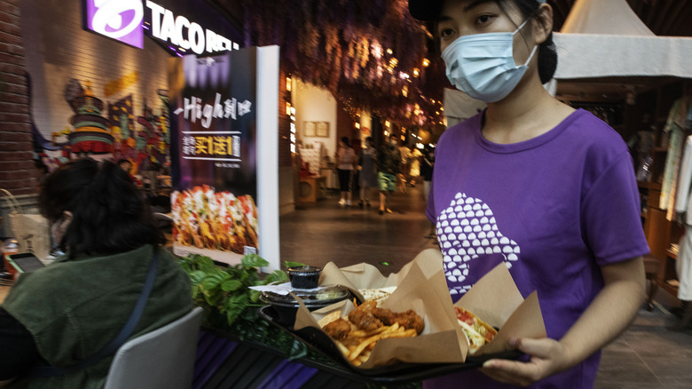 An employee delivers a tray of food at a Taco Bell restaurant operated by Yum China Holdings Inc. in Beijing, China, on Saturday, Sept. 5, 2020. 