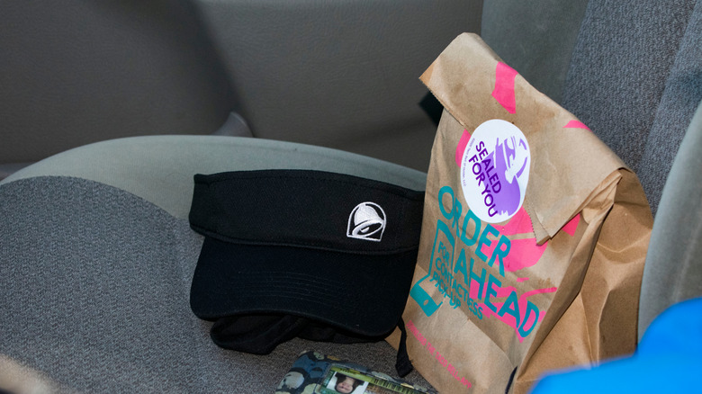 A Taco Bell black visor, bag and Wayne State University ID laying on the passenger side seat. 