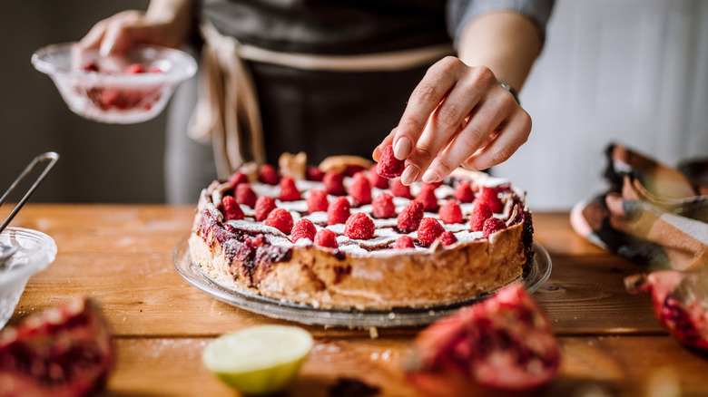 baker putting raspberries on pie