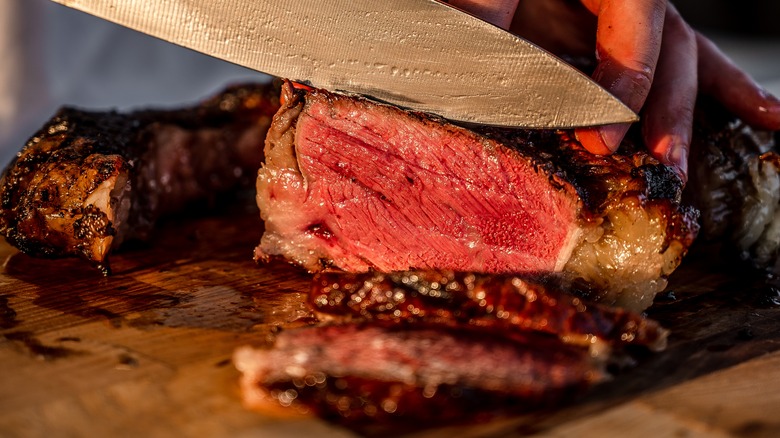 chef cutting medium rare steak