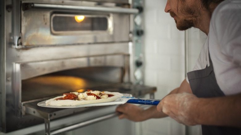 putting pizza in commercial oven