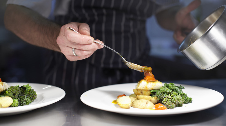 chef spooning sauce onto vegetables