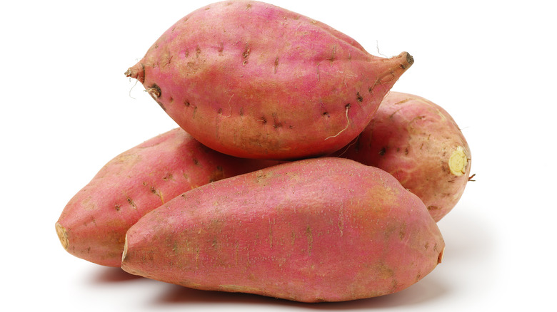 Sweet potatoes stacked against white background