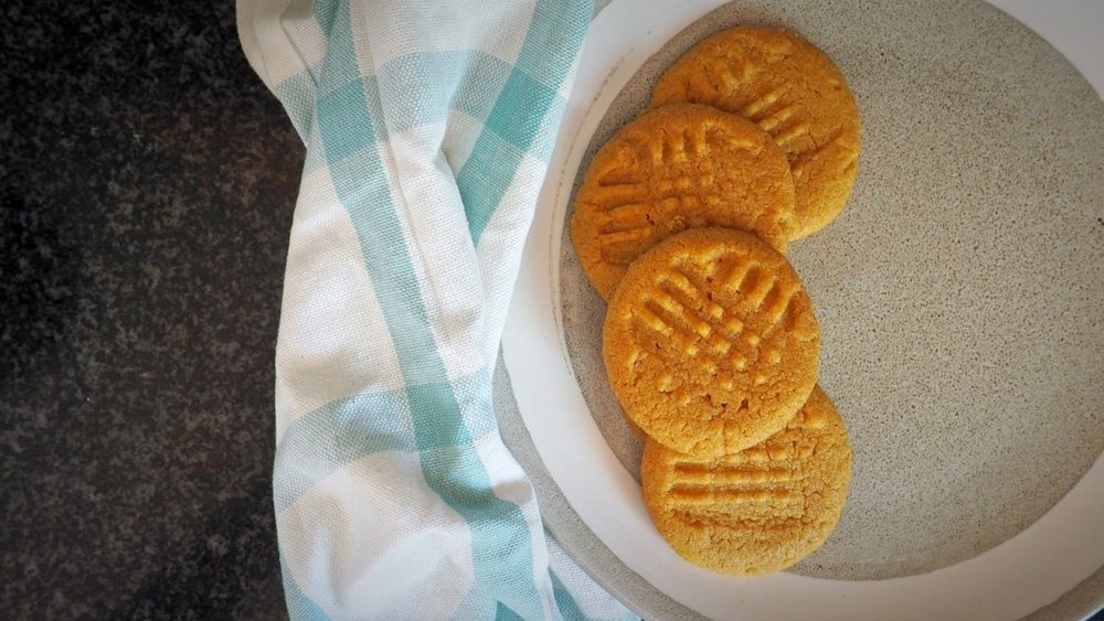 peanut butter cookies on a plate sitting on a hand towel on a counter