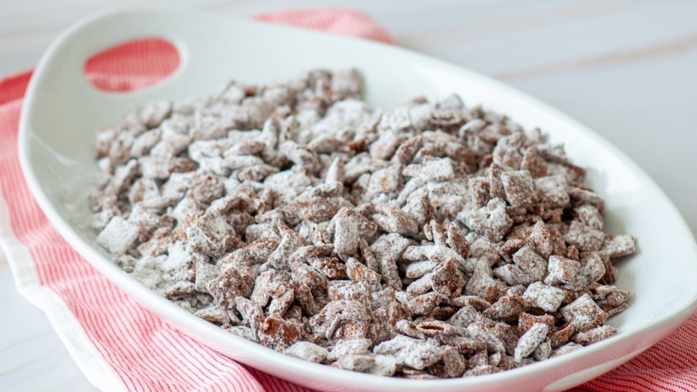 white bowl filled with puppy chow sitting on a red and white checked hand towel