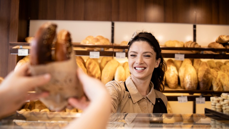 employee handing bag of bread