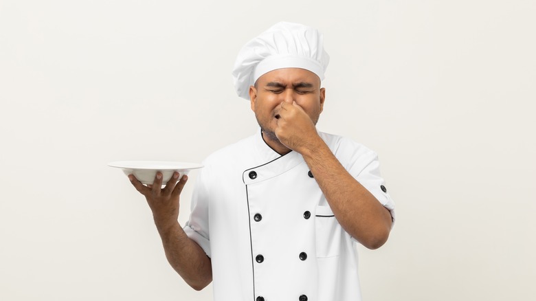 chef holding nose and dish