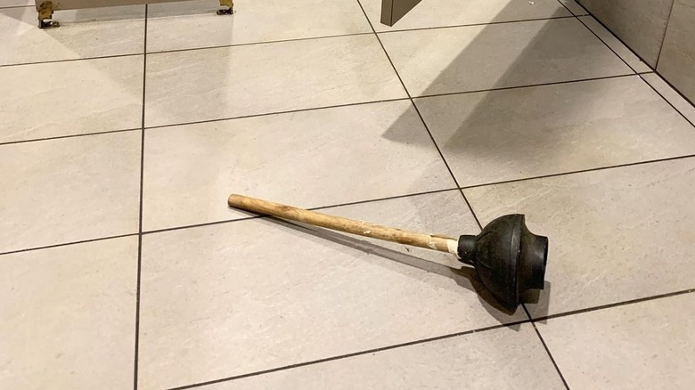 plunger on floor, restaurant bathroom