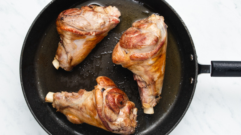 lamb shanks cooking in pan 