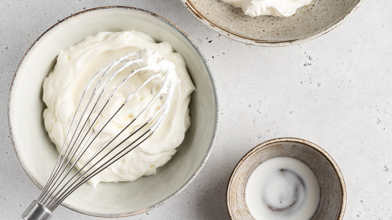 Whipping cream with whisk in bowl