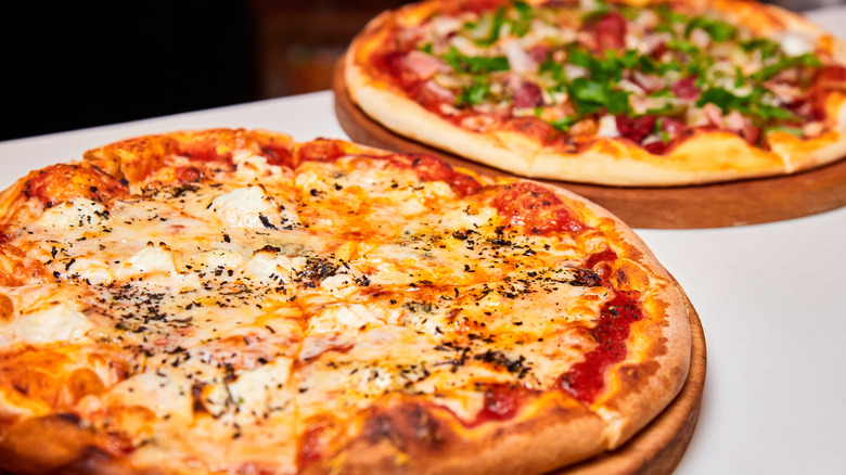 two pizzas on wooden platters